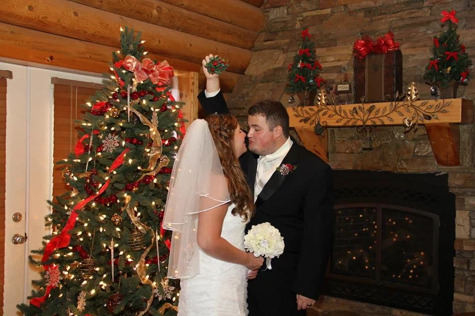 Wedding couple by a decorated Christmas tree and stone fireplace at Moose Hollow Lodge in Pigeon Forge