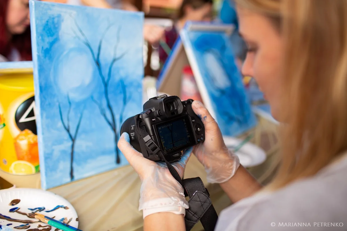Guest photographing blue canvas painting during retreat workshop at Moose Hollow Lodge in Pigeon Forge