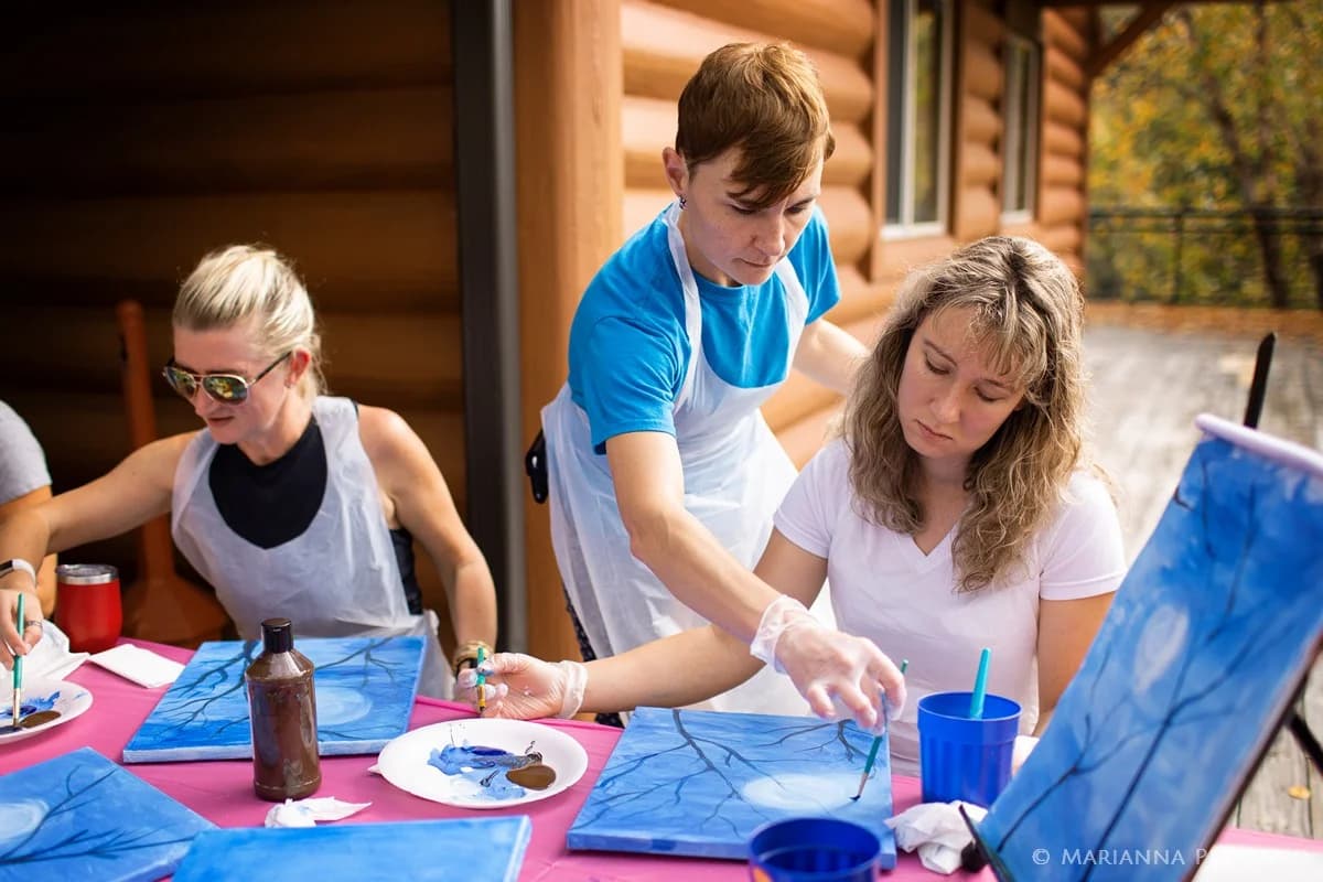 Group painting class on a rustic cabin deck near the Smoky Mountains at Moose Hollow Lodge in Pigeon Forge.