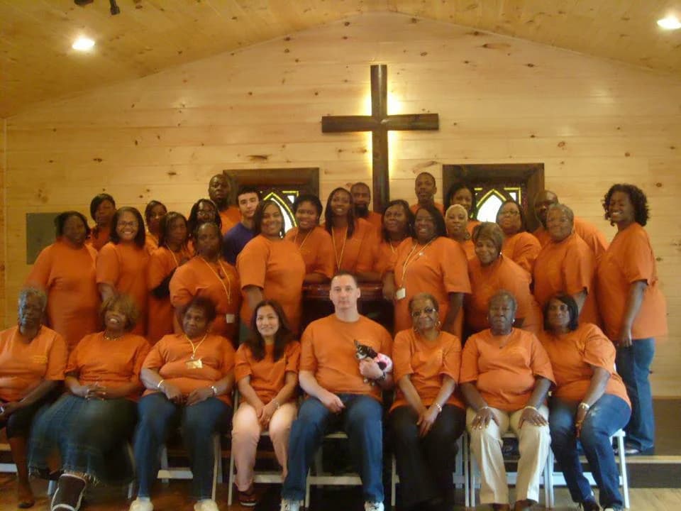 Large group gathered in a rustic wood-paneled chapel with a wooden cross at Moose Hollow Lodge in Pigeon Forge