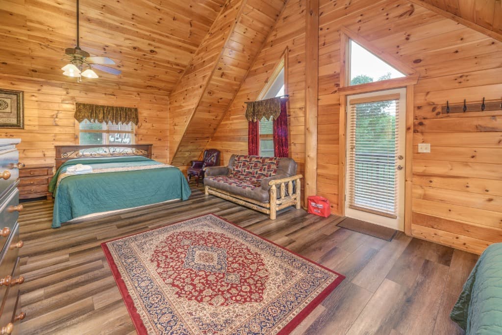 Rustic bedroom with king bed, log futon, and vaulted wood ceilings at Moose Hollow Lodge in Sevierville