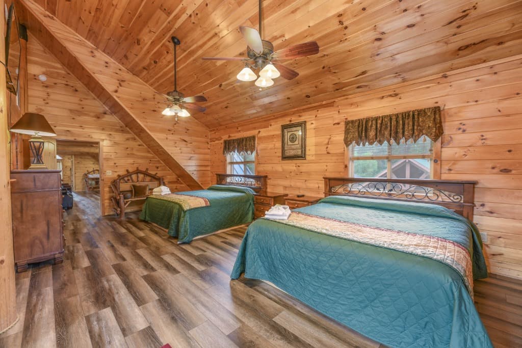 Rustic cabin bedroom with two beds and vaulted wood ceilings at Moose Hollow Lodge in Sevierville