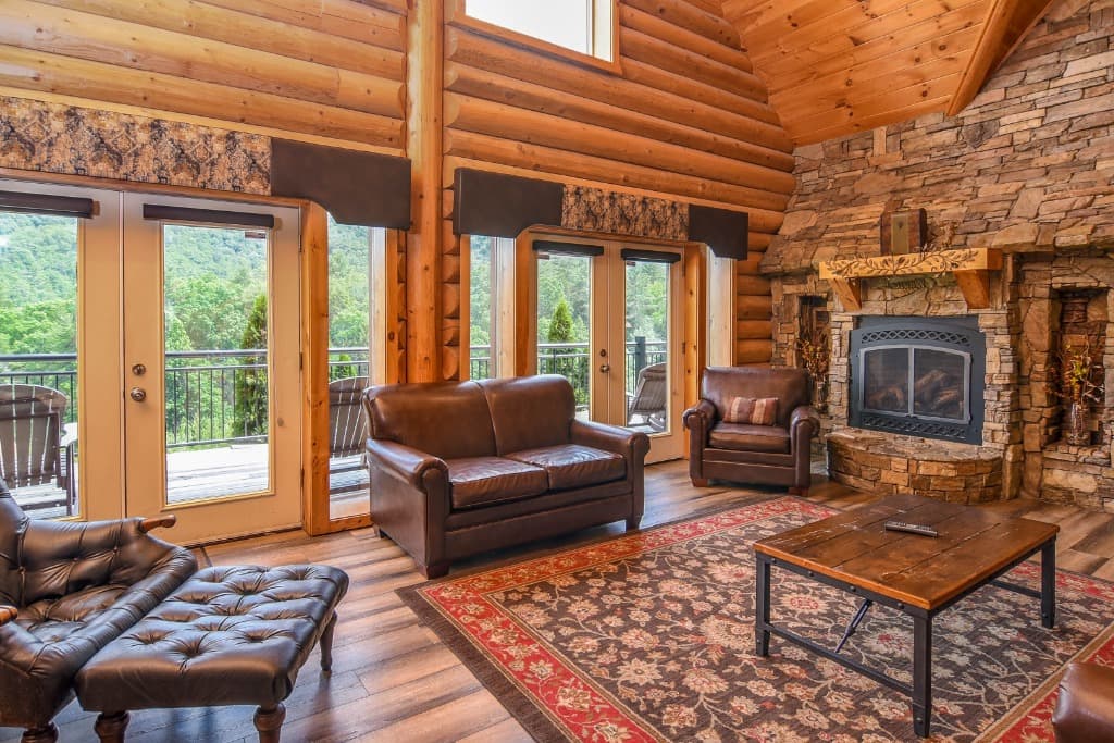 Rustic living room with stone fireplace, leather seating, and mountain views at Moose Hollow Lodge in Sevierville, TN
