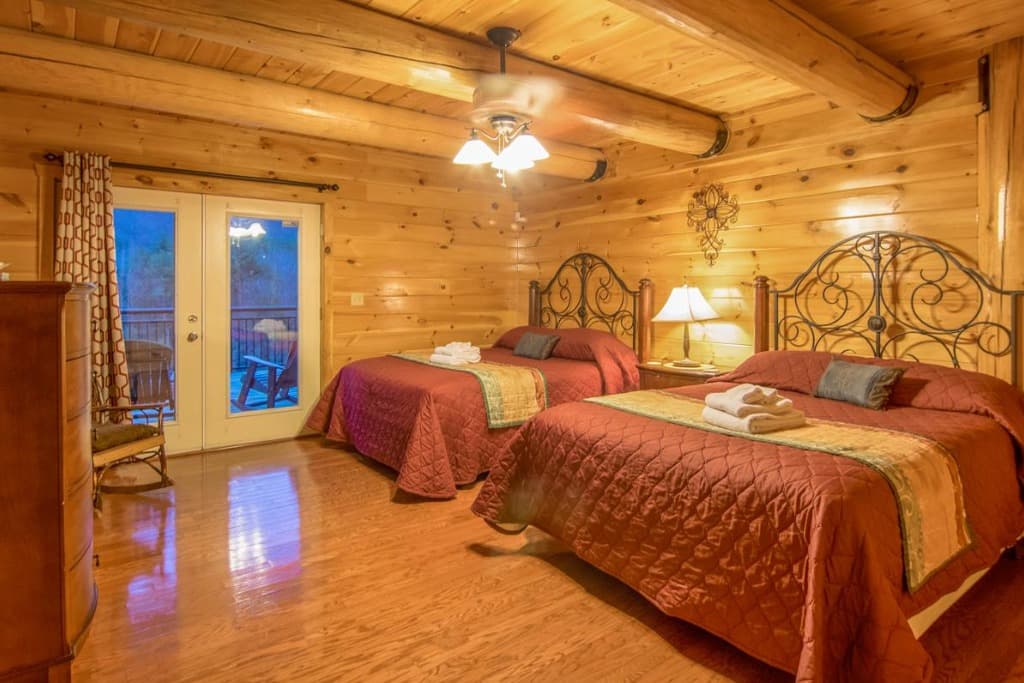Rustic bedroom with two beds, iron headboards, and deck access at Moose Hollow Lodge in Sevierville