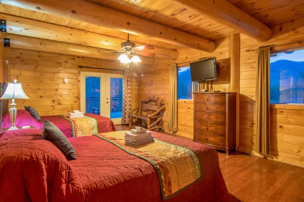 Rustic log cabin bedroom with two beds and deck access at Moose Hollow Lodge in Sevierville
