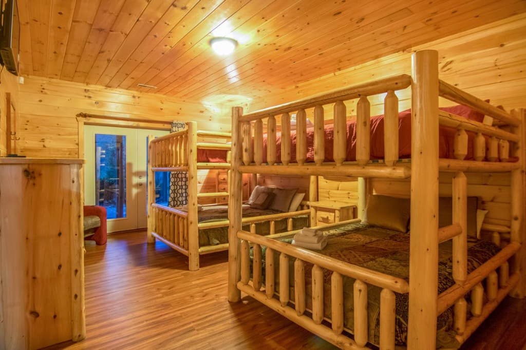 Spacious rustic bedroom with log bunk beds and wood paneling at Moose Hollow Lodge in Sevierville
