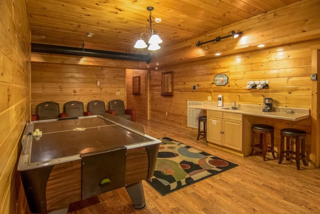 Rustic game room with air hockey table, theater seating, and wet bar at Moose Hollow Lodge in Sevierville