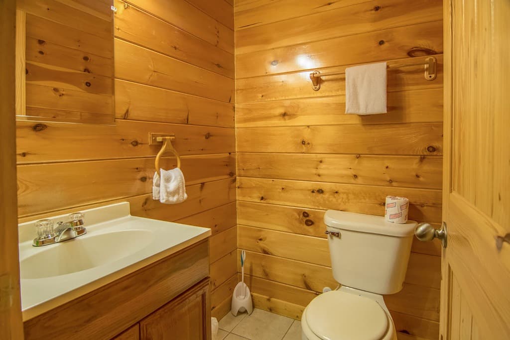Rustic wood-paneled bathroom with white vanity and toilet at Moose Hollow Lodge in Sevierville, TN