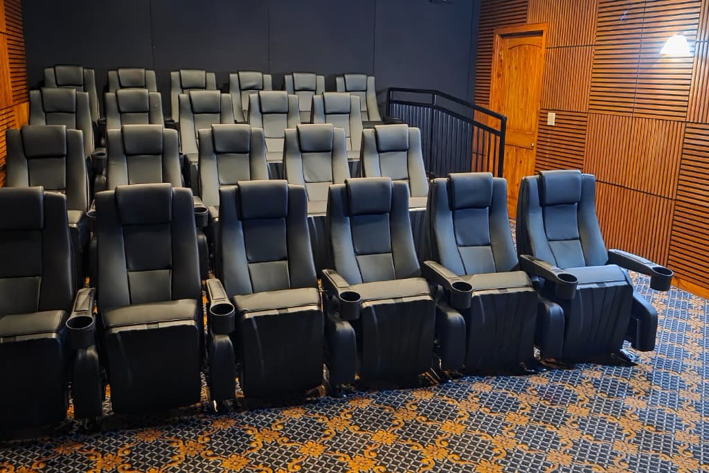 Luxury vacation rental home theater room with tiered black leather recliners, cup holders & patterned carpet. Ideal for mo...