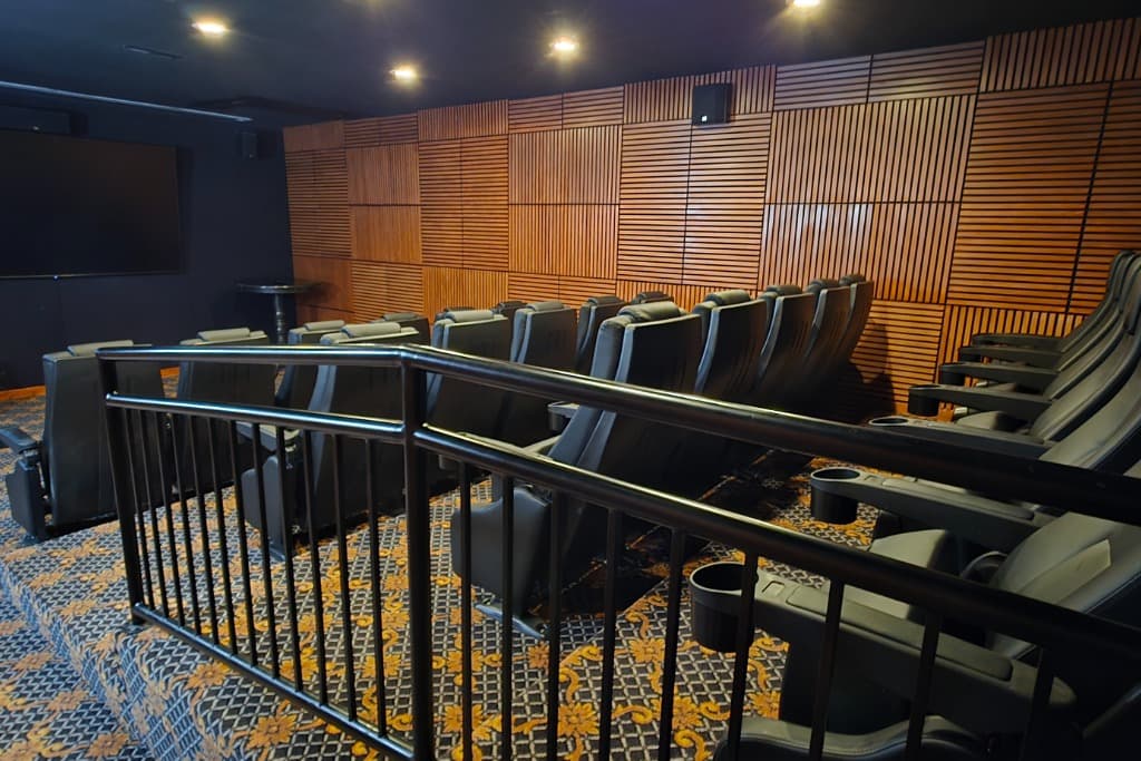 Luxury vacation rental theater room with tiered rows of cinema recliners, large screen, and acoustic wood paneling. Perfec...